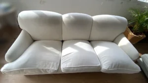 Sofá de 3 plazas blanco con manchas oscuras en cojines de respaldo antes de la limpieza en el Barrio de Salamanca, Madrid