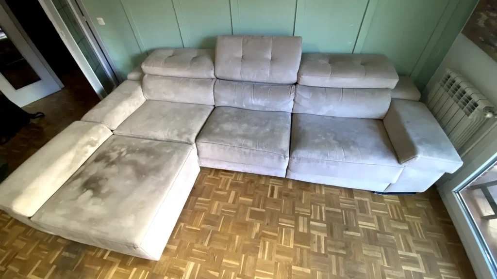 Sofá chaiselongue con extensas manchas acumuladas antes de la limpieza en Las Rozas