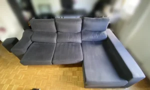 Sofá chaiselongue gris oscuro apagado por el polvo y el roce antes de la limpieza en La Moraleja, Madrid