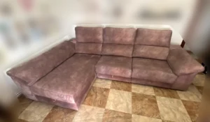 Gran sofá chaiselongue de microfibra oscura con aspecto empolvado antes de su limpieza en Puerta del Ángel