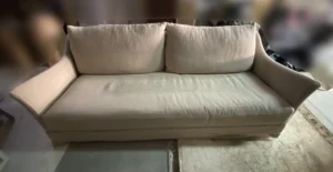 Sofá de lino natural con pérdida de color y polvo acumulado en los asientos antes del lavado