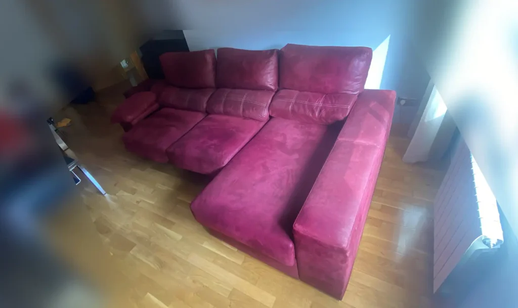 Sofá chaiselongue rojo de microfibra con suciedad acumulada y color apagado antes de su limpieza en Carabanchel