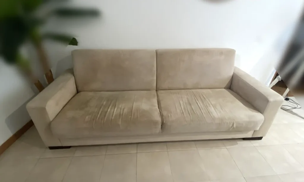 Sofá beige de microfibra con fuertes manchas de roce y pliegues oscurecidos en la zona norte de Madrid